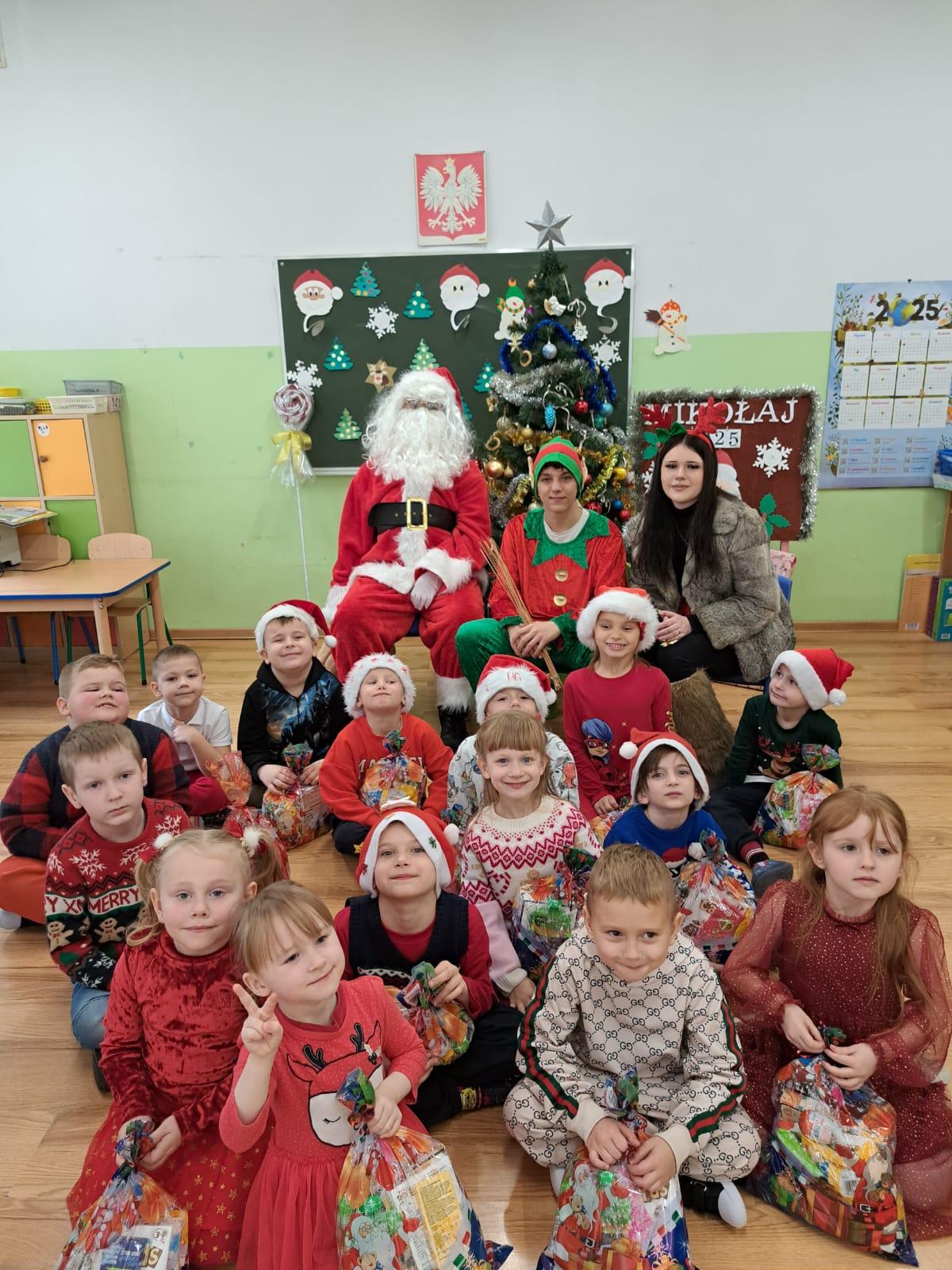 Grupa dzieci z paczkami i Mikołajem
