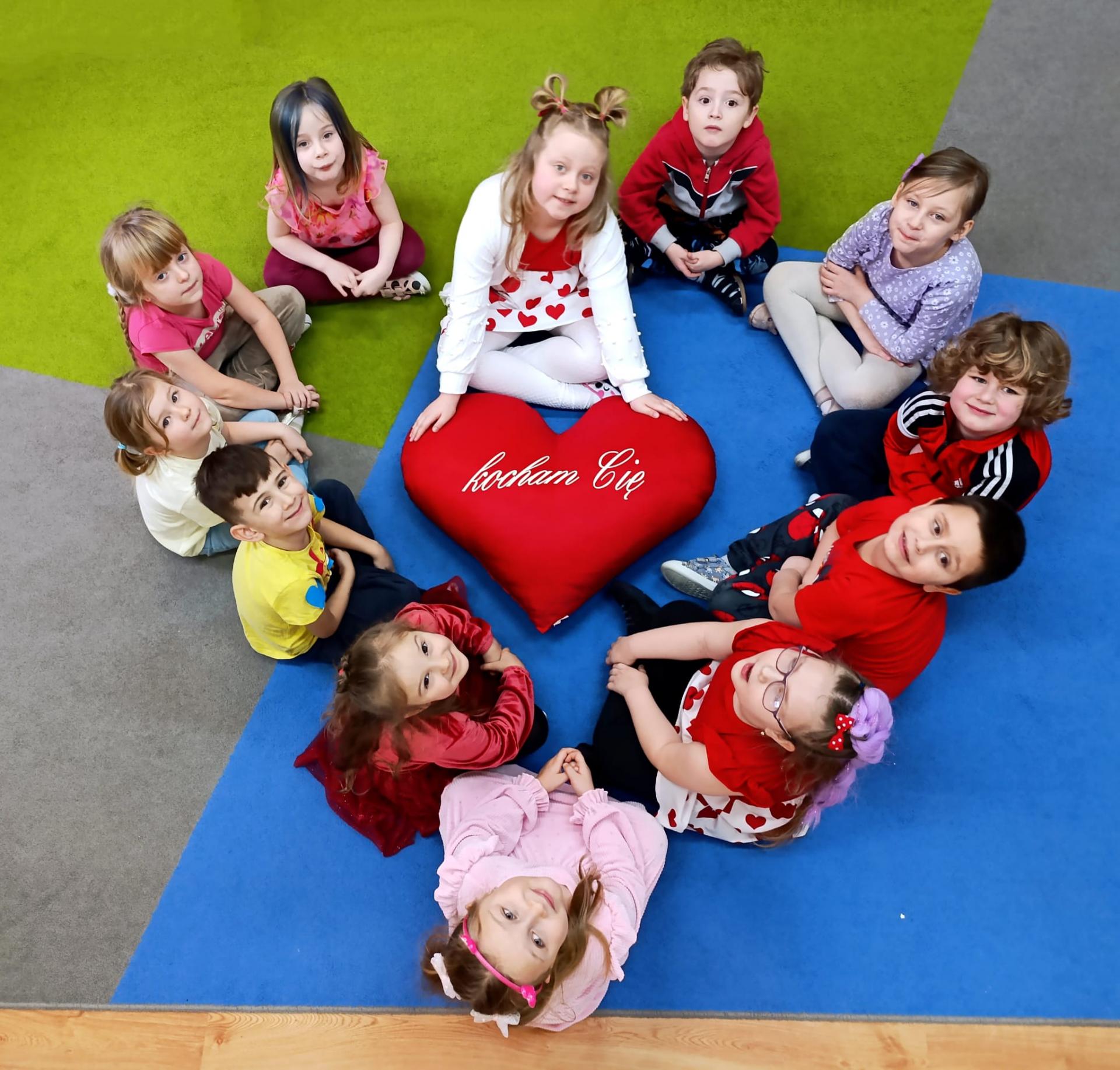 Dzieci siedzące na dywanie tworzą kształt serca