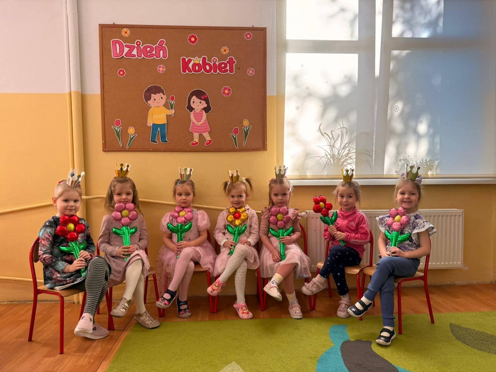 Dziewczynki siedzące na krzesełkach z kwiatami