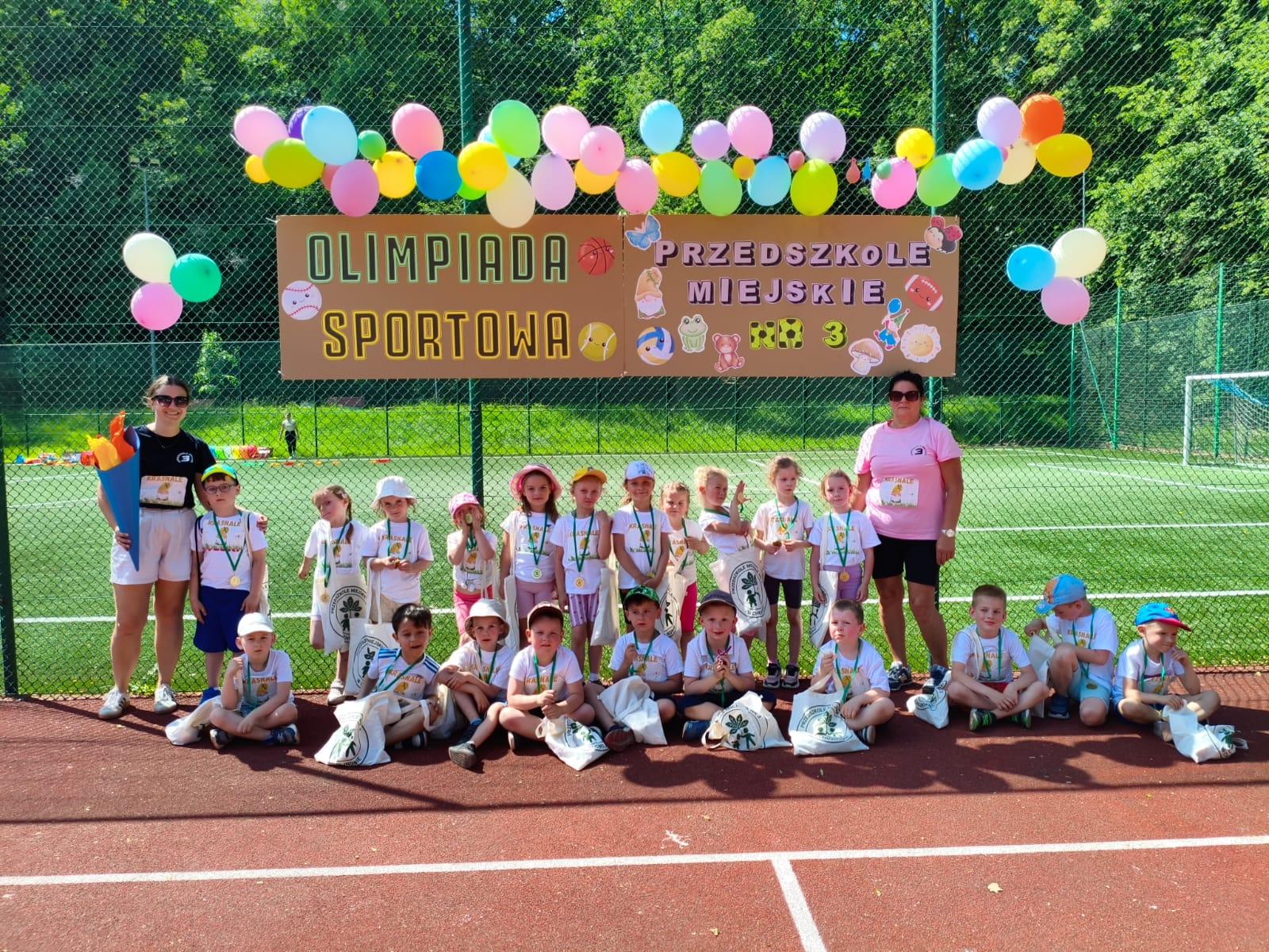 Dzieci z paniami pod napisem olimpiada sportowa